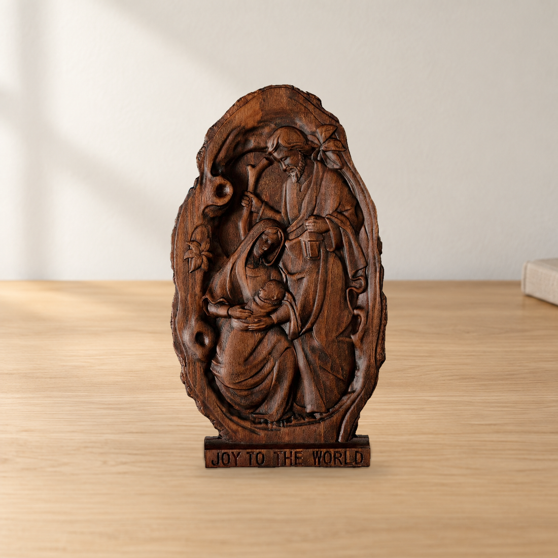 Wooden Nativity scene plaque on a tabletop with JOY TO THE WORLD carved into its base.