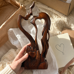 Wooden couple sculpture in a gift-opening scene; packaging shown is not an included-item specification
