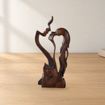 Wooden couple sculpture in an illustrative tabletop setting; not a scale reference